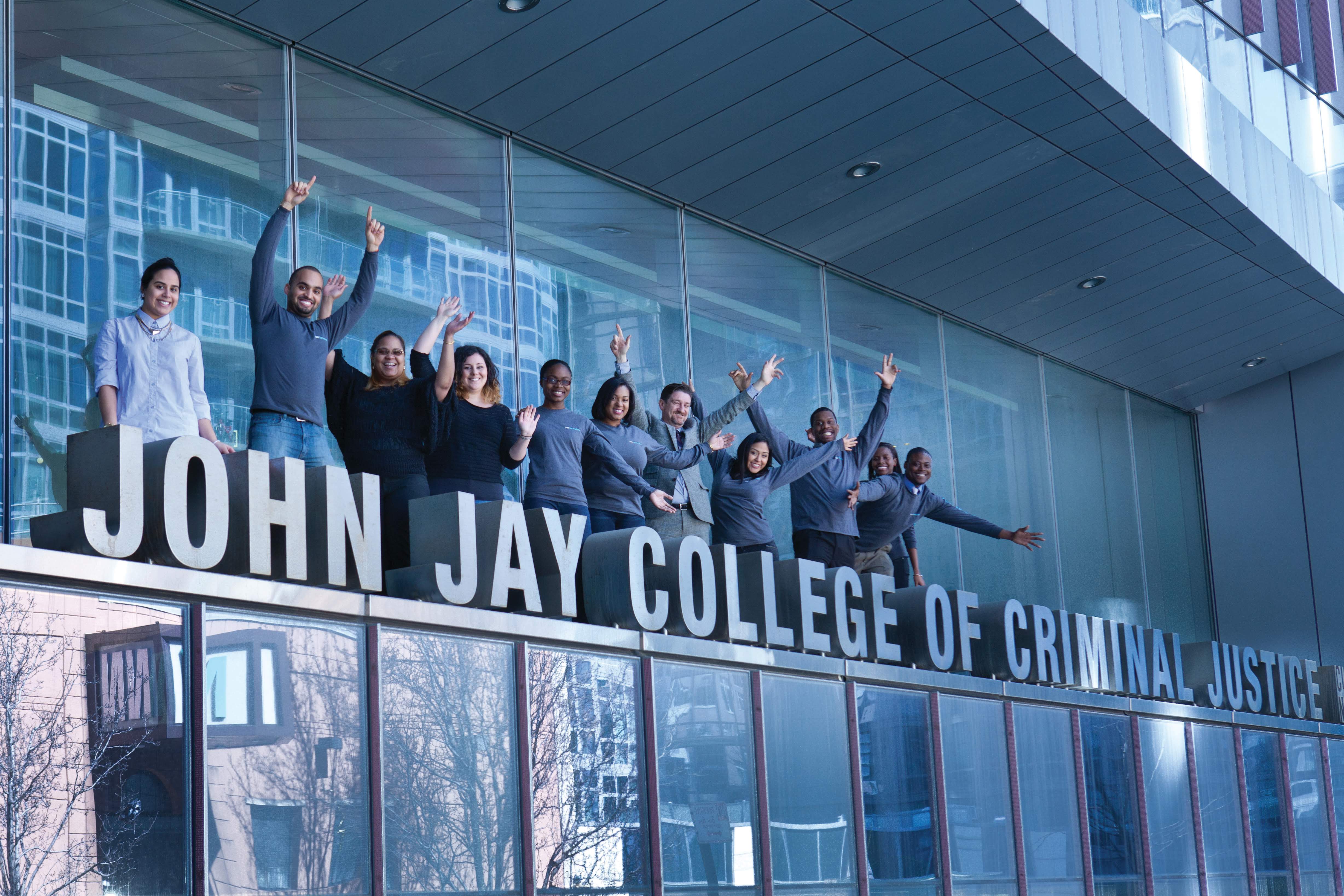 Students posing behind the John Jay College sign