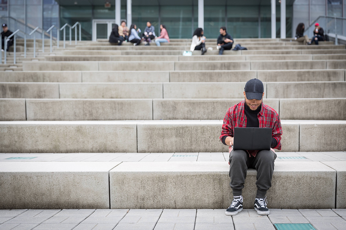 Student sitting on steps working on laptop