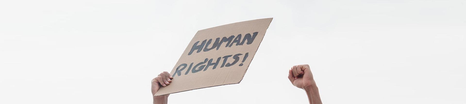 Hand holding a sign that says Human Rights