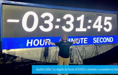 Justin Colón ’23 stands in front of NASA’s Artemis I countdown clock 
