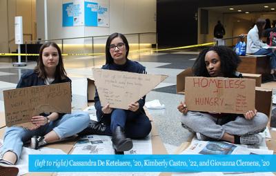 students sitting with homeless signs